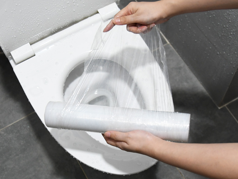 Bọc màng thực phẩm quanh miệng bồn cầu thật kín