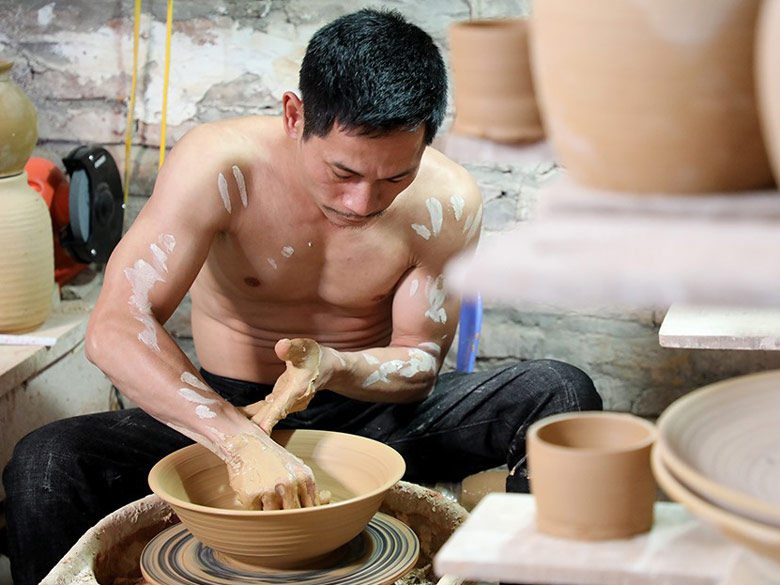 Người thợ sử dụng chân đạp bàn xoay rồi dùng hai tay để chuốt