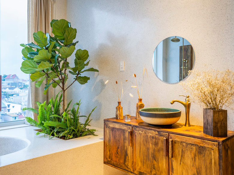 Chậu sứ mỹ thuật và vòi nước bằng đồng được đặt trên bàn gỗ mộc mạc